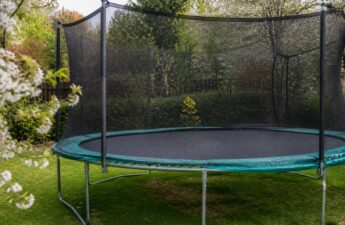 Trampoline in een tuin met zicht op springmat, randkussen en veiligheidsnet