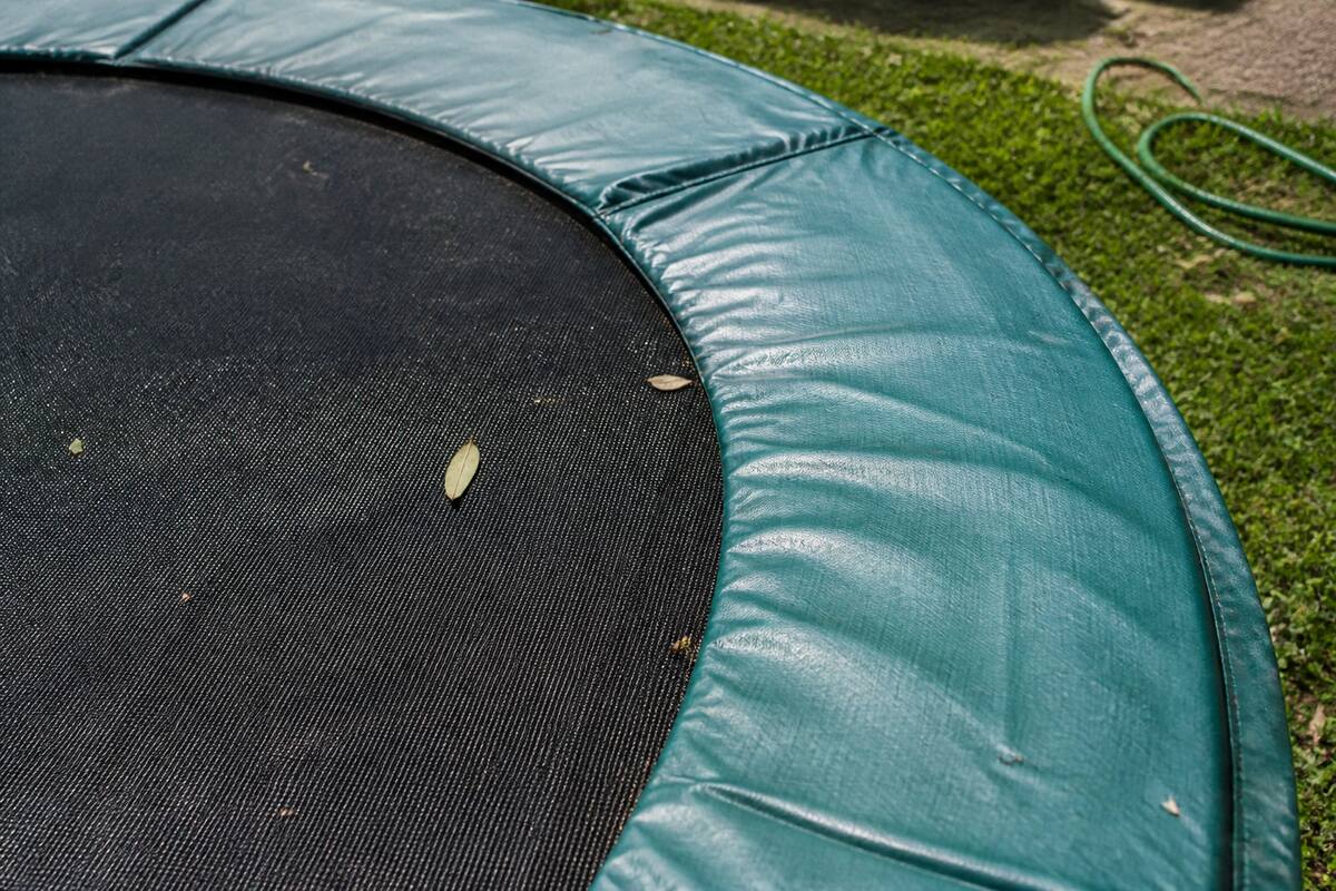 Springmat en randkussen van een trampoline schoonmaken in een tuin