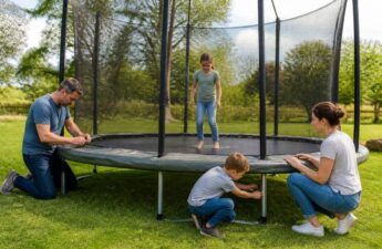 Gezin dat een trampoline opbouwt in de tuin met veiligheidsnet en randkussen