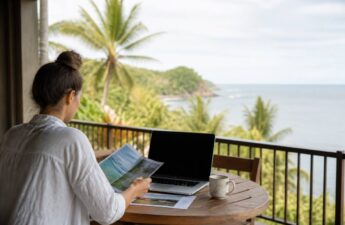 Iemand vergelijkt reisopties op een laptop met papieren reistips voor een rustige vakantiekeuze